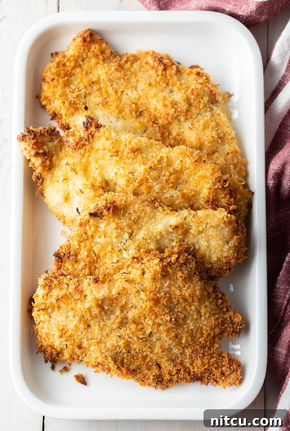 Baked chicken cutlets on platter, ready to be served, looking golden and crispy.