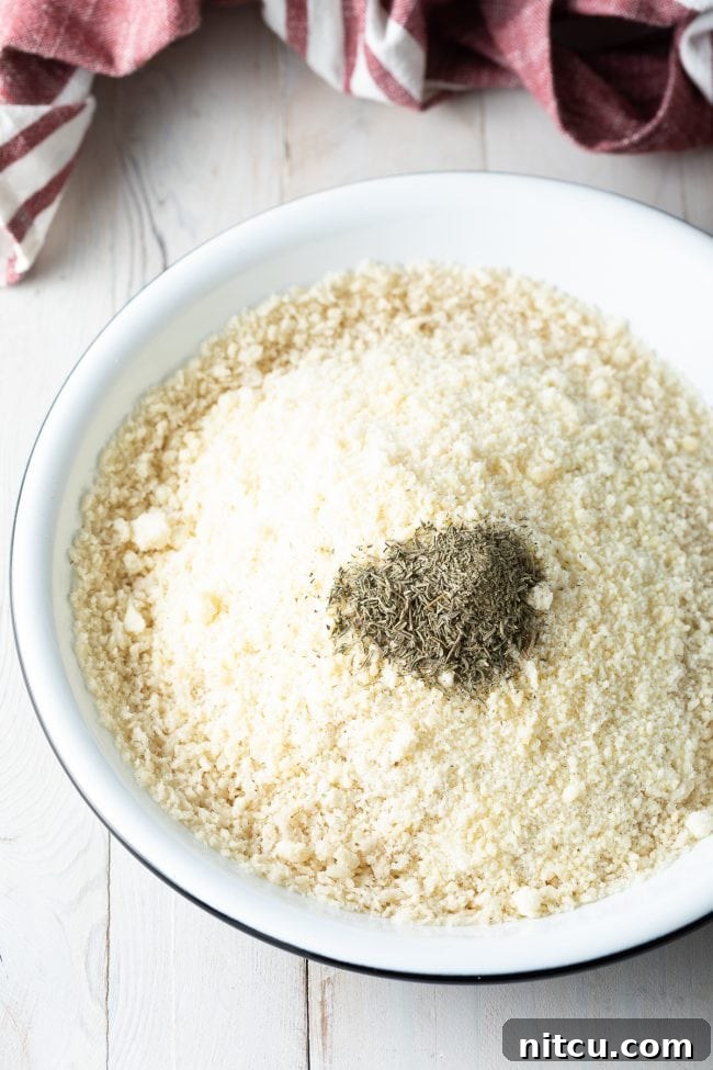 Closeup of ingredients for breadcrumb mixture in a bowl, including panko and parmesan.