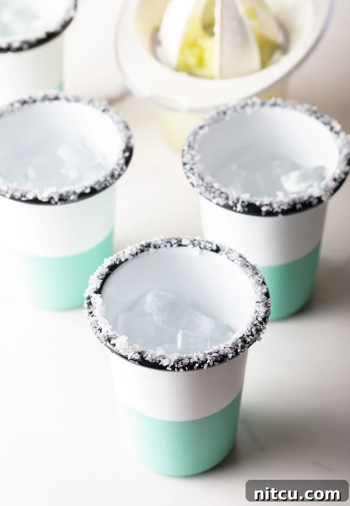 4 blue and white striped cups, with salt around the rim.
