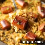 Close view of a piece of cooked sausage on a spoon with sauerkraut.