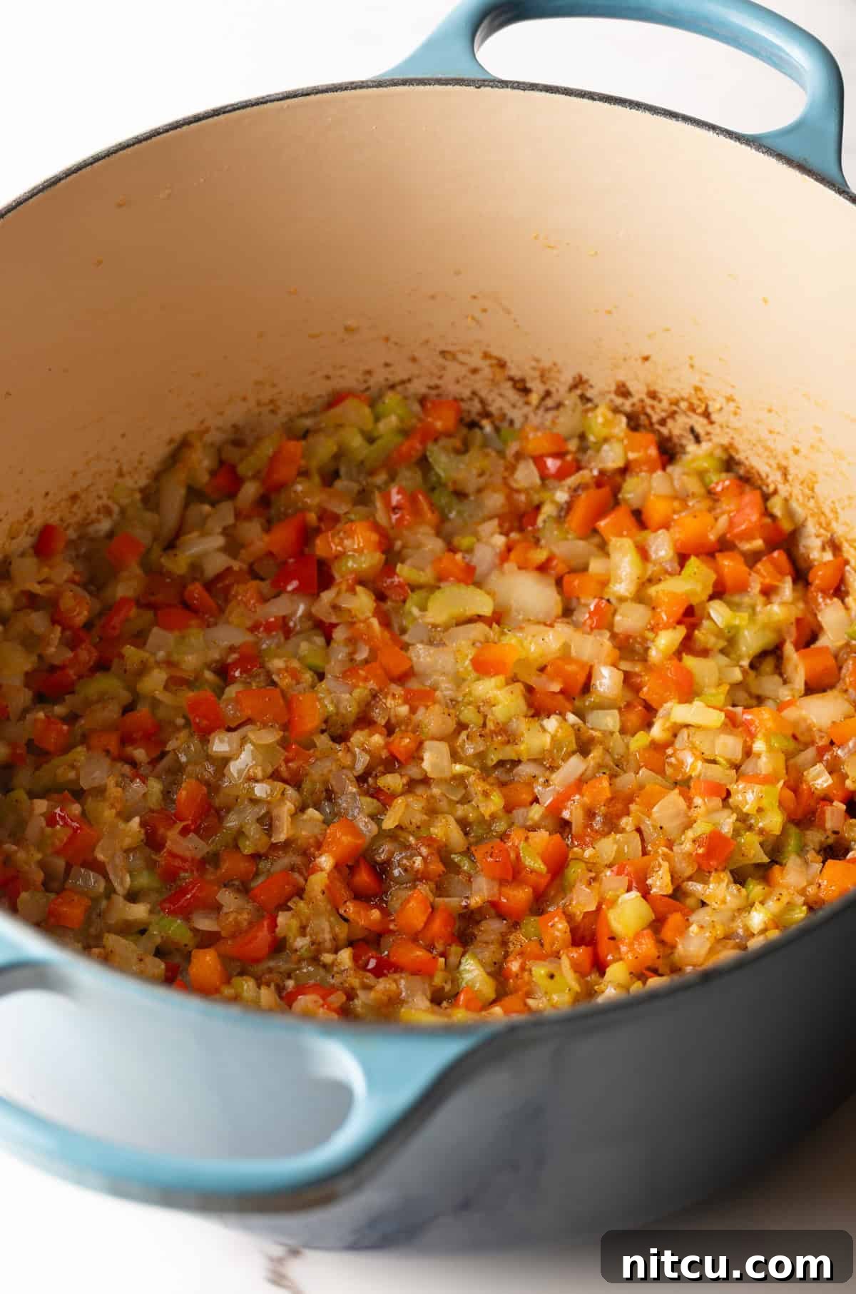 Vegetables being sautéed in a pot for the Cajun macaroni and cheese recipe.