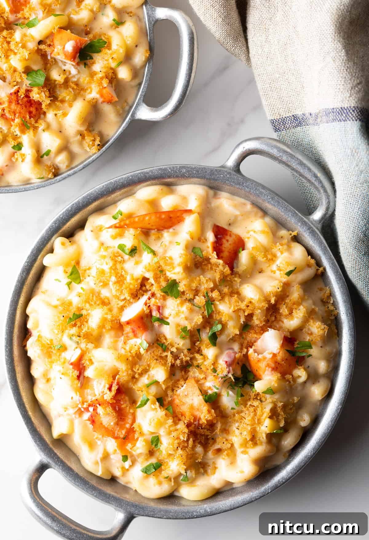 Two metal bowls filled with creamy lobster mac and cheese.
