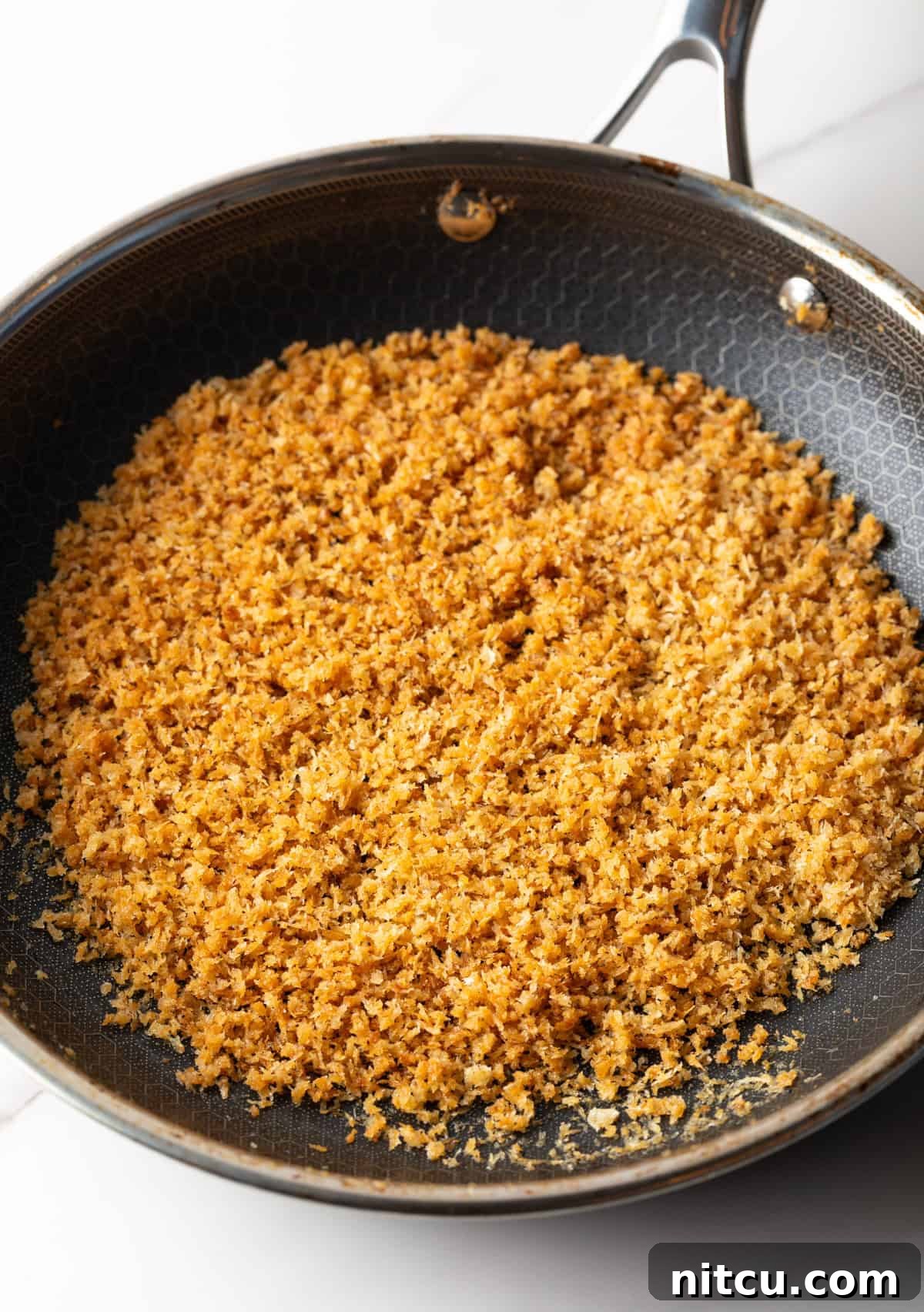 Breadcrumbs are being toasted in a skillet.
