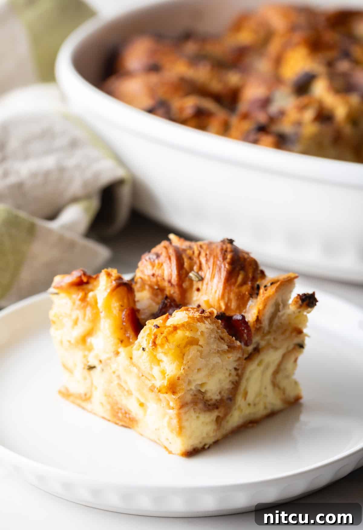 A delectable slice of croissant breakfast casserole resting on a white plate, showcasing its fluffy layers.