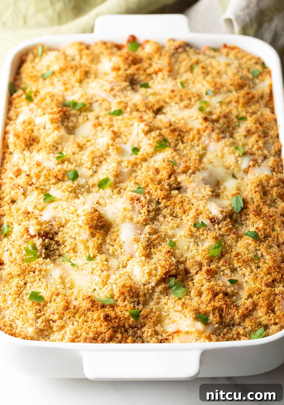 A fully baked chicken parmesan casserole in a white baking dish, with a golden-brown crispy topping and bubbling sauce.