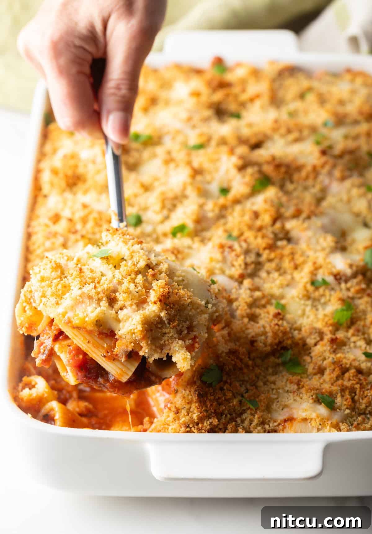 A large white baking dish filled with delicious chicken parmesan casserole, showing the rich layers and crispy topping.