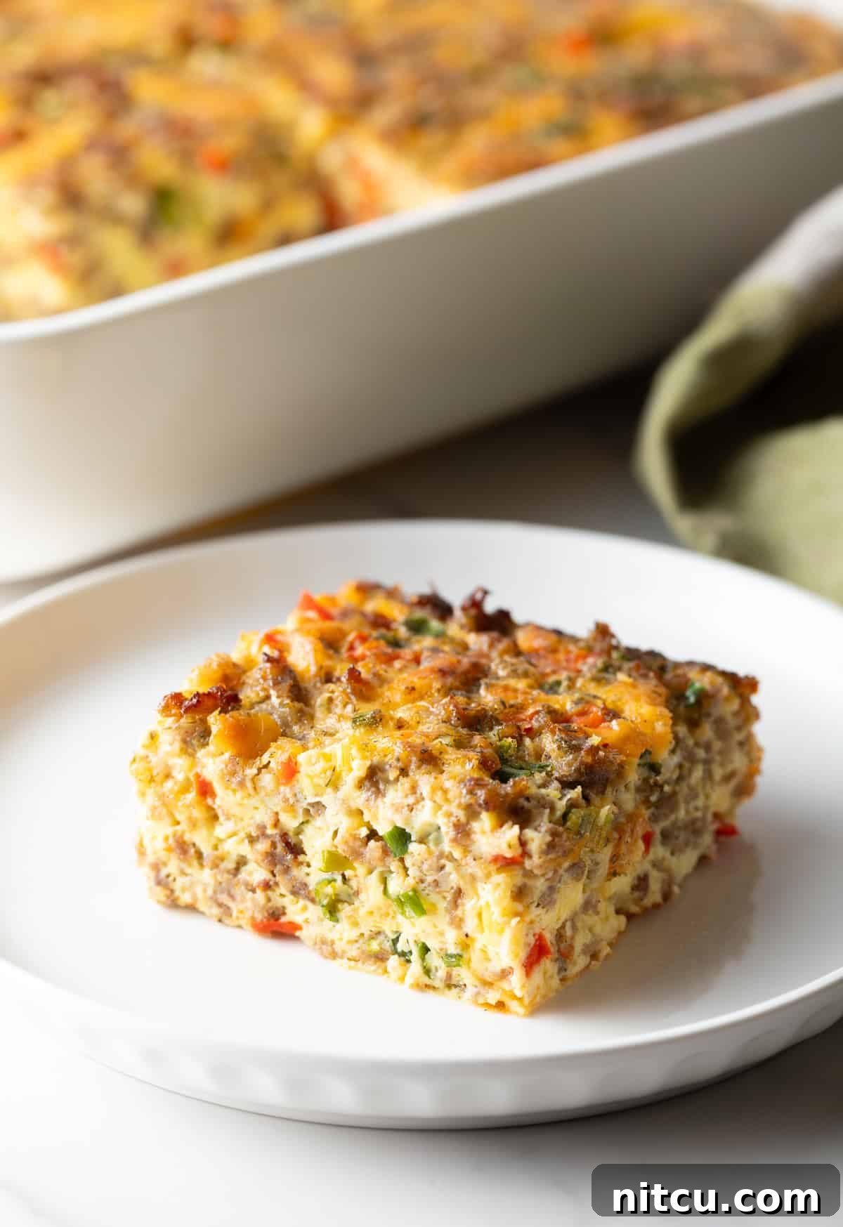 Square of sausage breakfast casserole on a white plate.