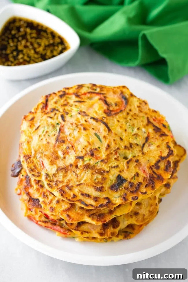 A perfectly cooked scallion and vegetable Korean pancake, Pajeon, freshly made and stacked on a plate, ready to be served and enjoyed.
