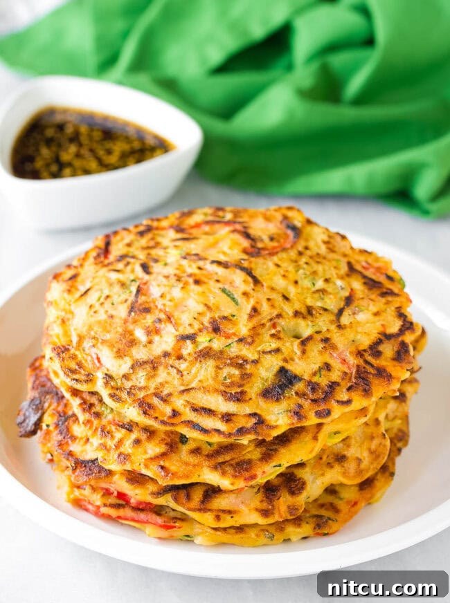 A stack of golden-brown Korean pancakes (Pajeon) resting on a clean white plate, showcasing their inviting crisp texture and fluffy interior.