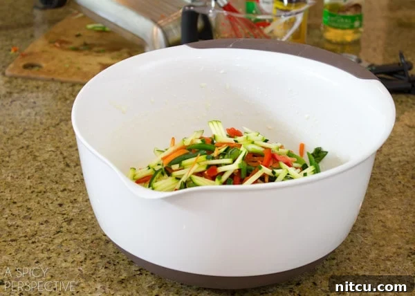 A vibrant bowl filled with perfectly julienned vegetables—carrots, bell peppers, and zucchini—ready to be incorporated into the savory Korean pancake batter.