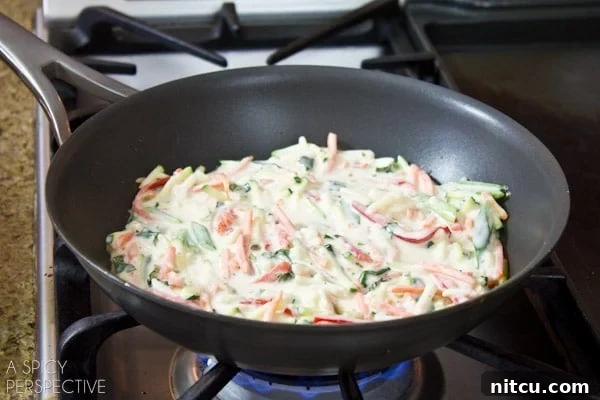 Several Korean pancakes (Pajeon) are shown sizzling and frying in a hot pan, their edges turning golden-brown, promising a delicious crispiness.