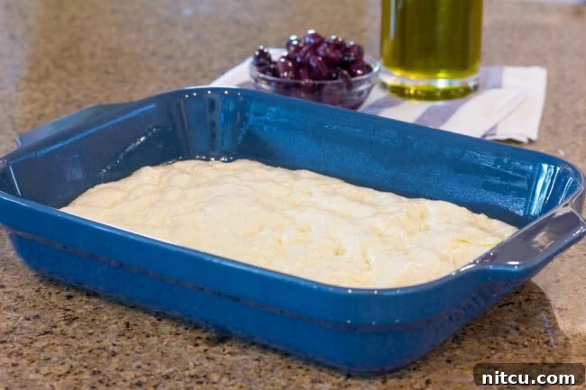 Blue baking dish with raw poked dough.
