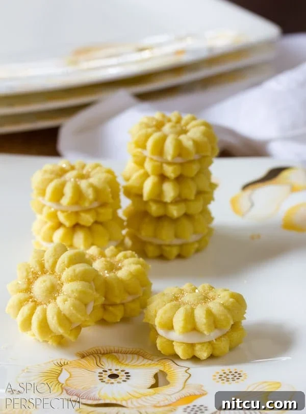 Lemon Cookies with Lemon Cream Filling - Spritz Cookies stacked on plate