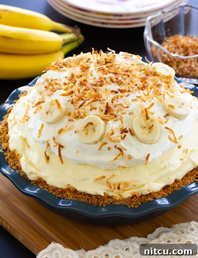 Finished Fluffy Banana Cream Pie topped with shredded coconut and fresh banana slices, ready to be chilled.