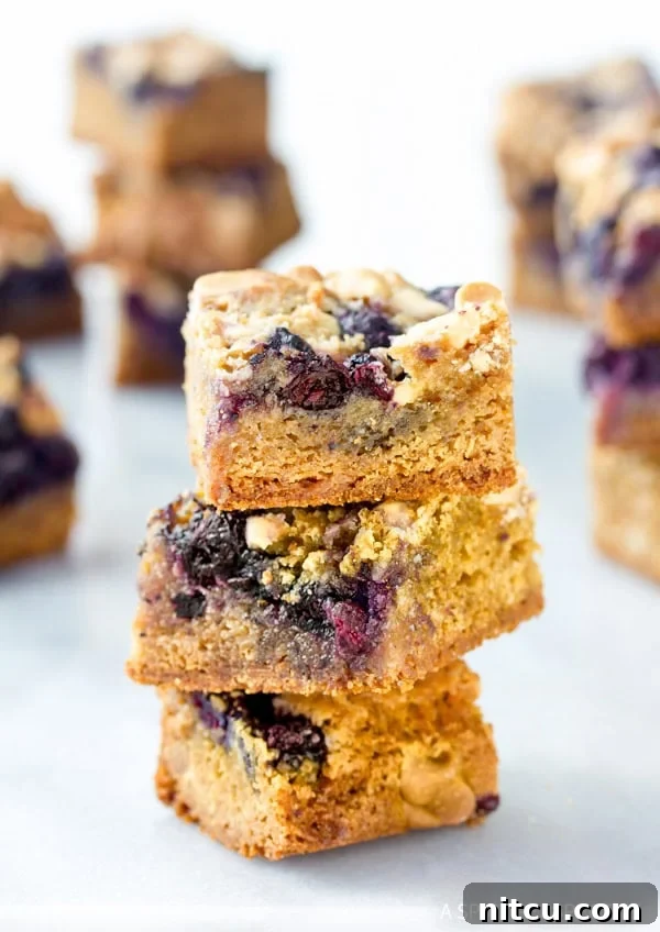 Three stacked Blueberry White Chocolate blondies showcasing their soft texture and vibrant blueberries.