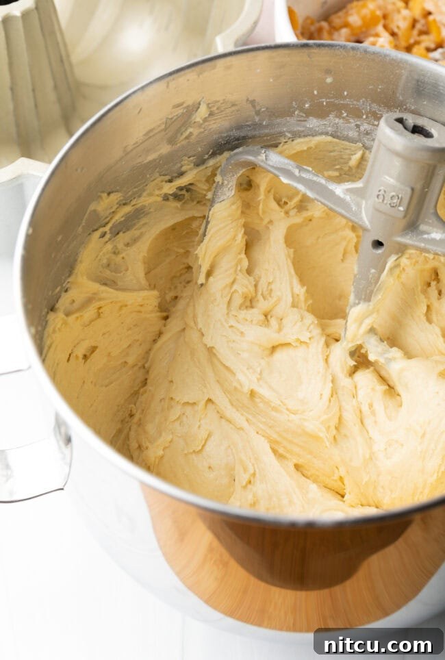 Creamy batter being poured into a greased bundt pan, showing the cake preparation.