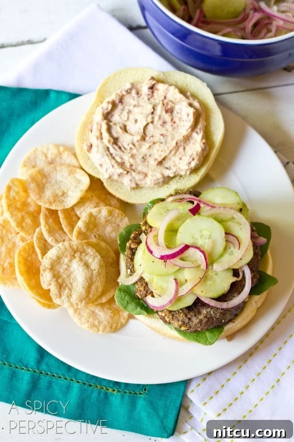 An overhead view of a plated Mediterranean burger, elegantly presented with a side of chips on a rustic surface.