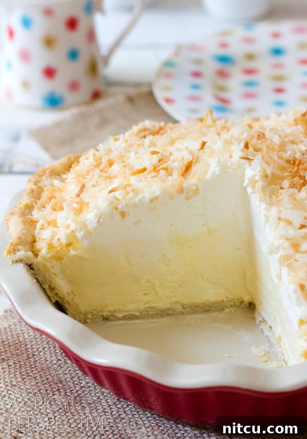 Coconut Pie Recipe with Cream of Coconut - whole pie with sliced cut out showing the inside of the thick cream pie