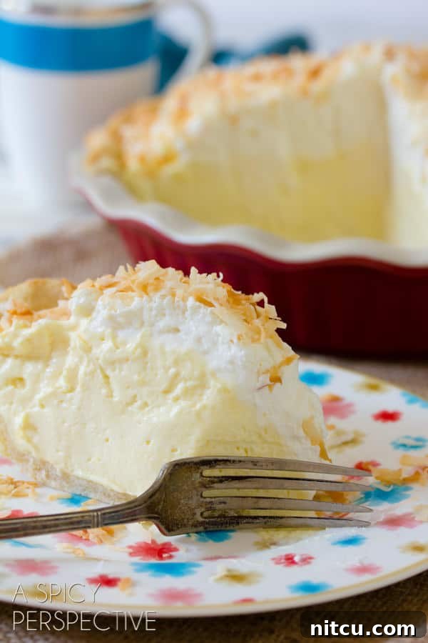 Coconut Cream Pie on plate with fork cutting through thick creamy layers