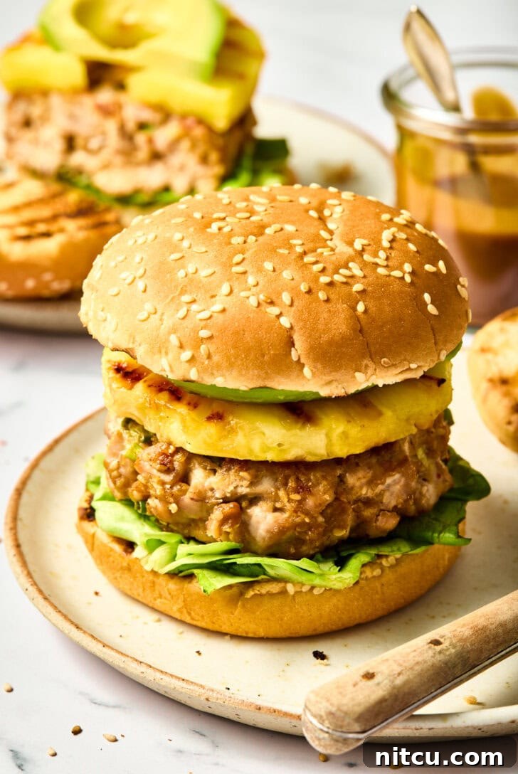 Ahi Tuna Burgers with Grilled Pineapple Recipe on plate, showcasing layers of fresh tuna, golden pineapple, and crisp lettuce on a bun