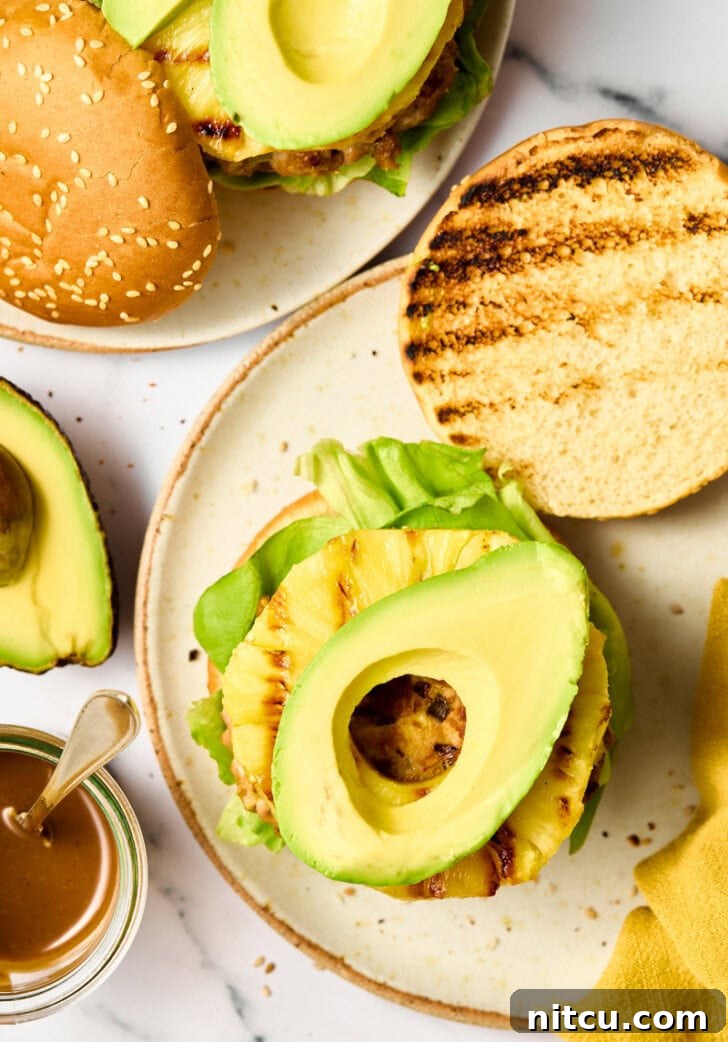 Healthy Tuna Burgers with Grilled Pineapple Recipe - an overhead shot of the completed burger on a plate with vibrant garnishes