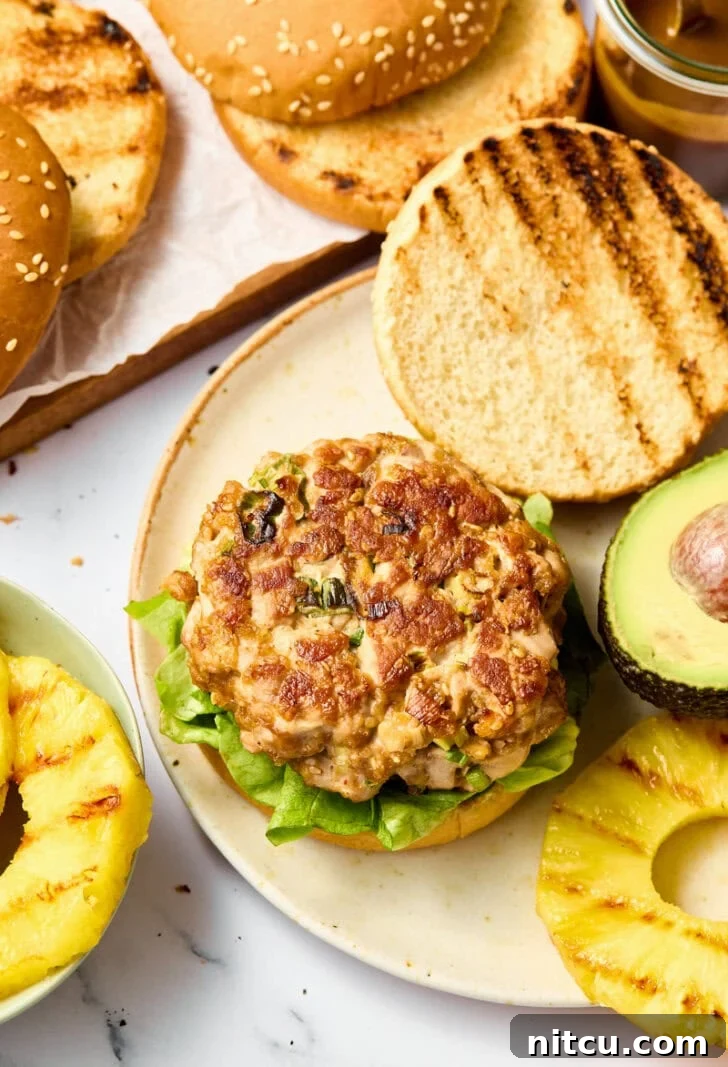 Stacked Ahi Tuna Burgers on buns with crisp lettuce and vibrant grilled pineapple, ready to serve