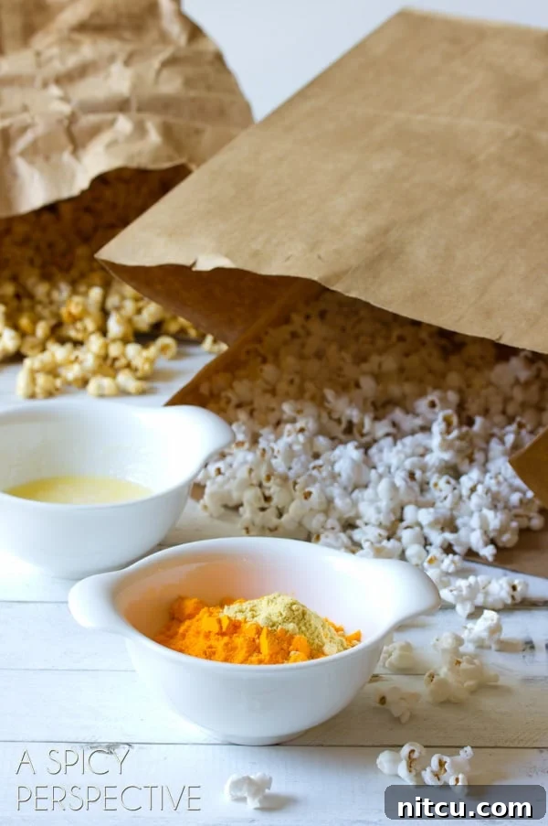 Two bags of popcorn behind a bowl of melted butter and cheese powder.