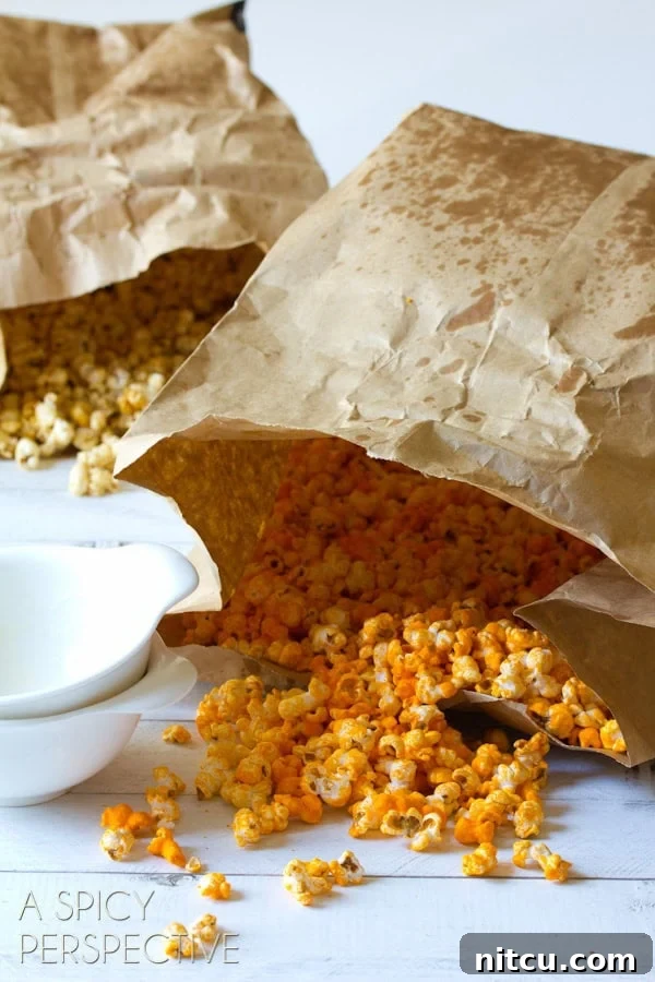 Two paper bags, one filled with caramel popcorn and the other filled with cheese popcorn.