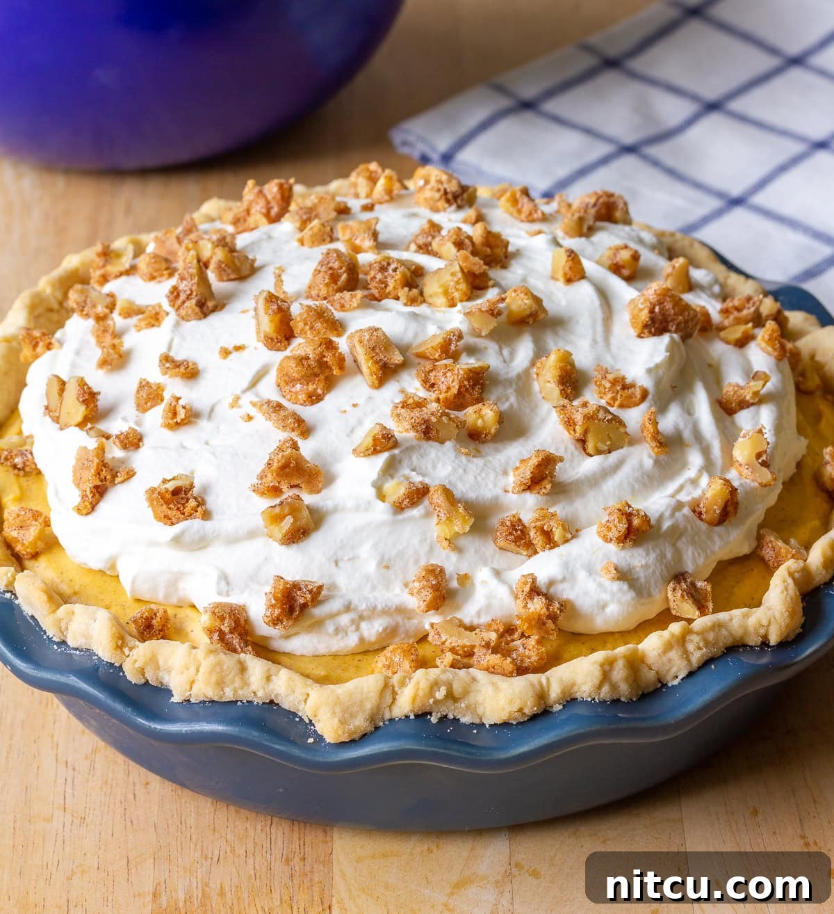 Close-up of a Pumpkin Cream Pie with a thick layer of pumpkin filling and a generous swirl of whipped cream on top