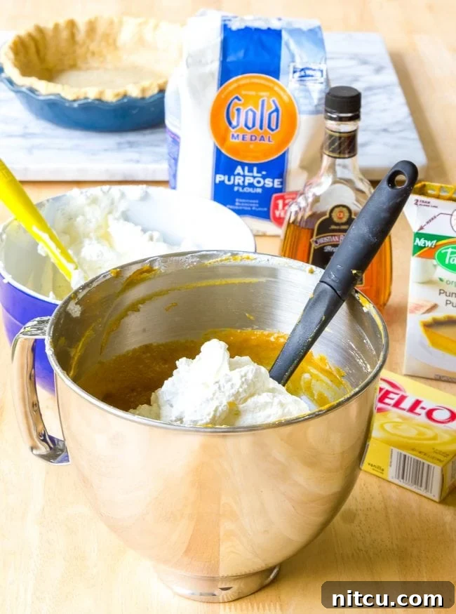 Assortment of ingredients for pumpkin cream pie laid out on a wooden surface