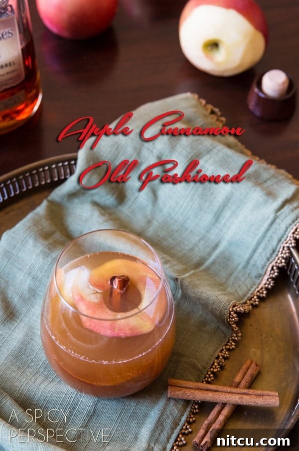 Cocktail with cinnamon sticks next to it and text saying 'apple cinnamon old fashioned'.