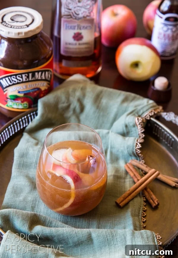 Apple cinnamon old fashioned cocktail on a serving platter with garnish of apple and cinnamon stick.