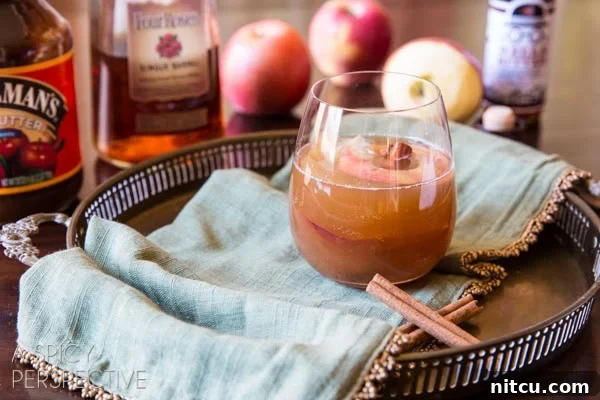 Apple cinnamon old fashioned served on a platter with cinnamon sticks.