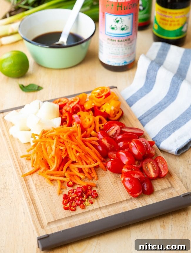Freshly chopped and prepared vegetables for Pad Kee Mao laid out on a wooden cutting board, showcasing the vibrant ingredients.