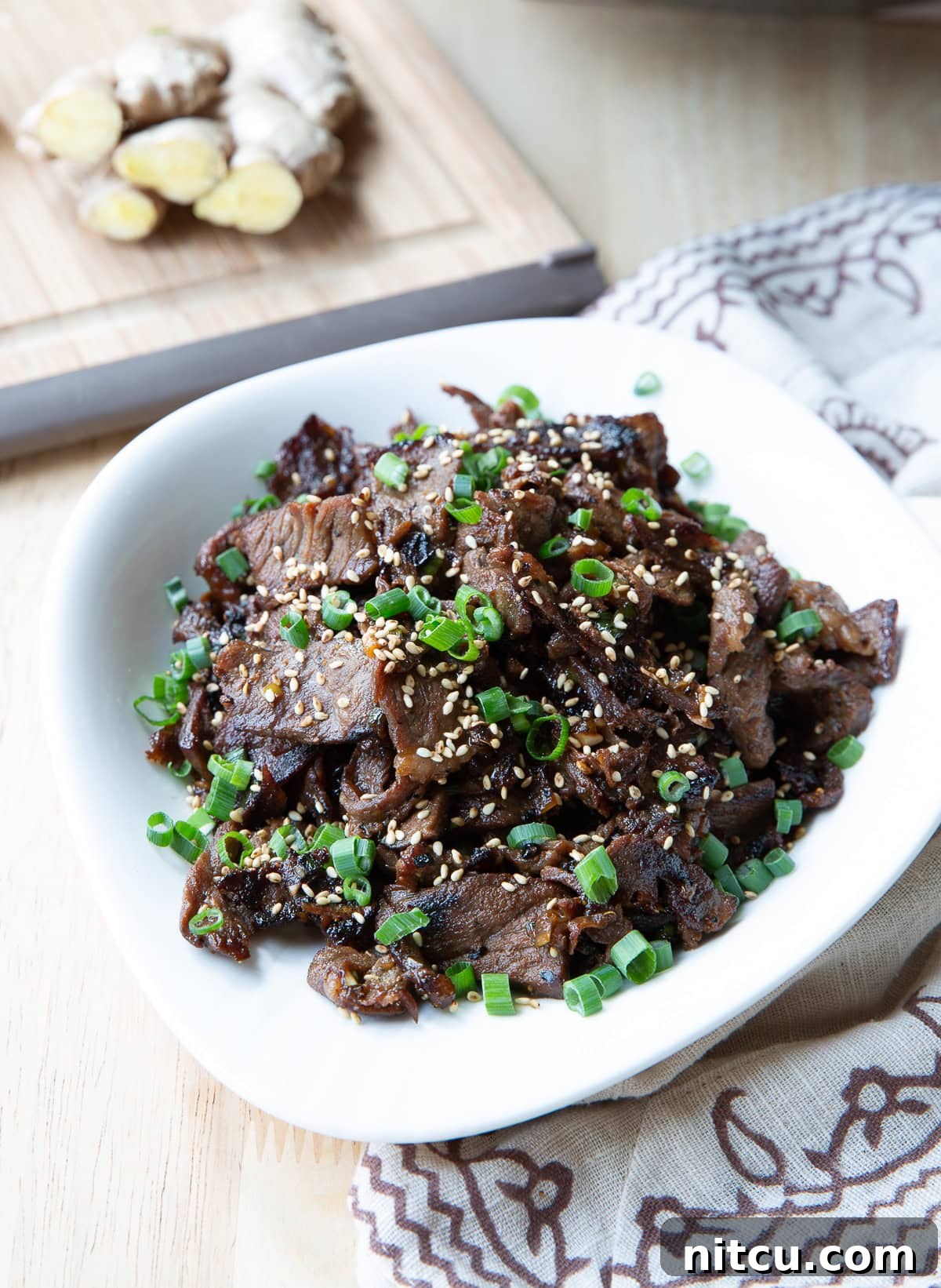 Beef bulgogi served in a white bowl topped with scallions and sesame seeds.