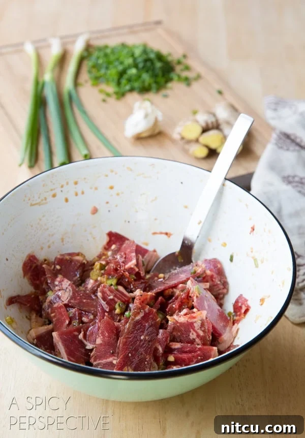Thin beef slices marinating in a white bowl.