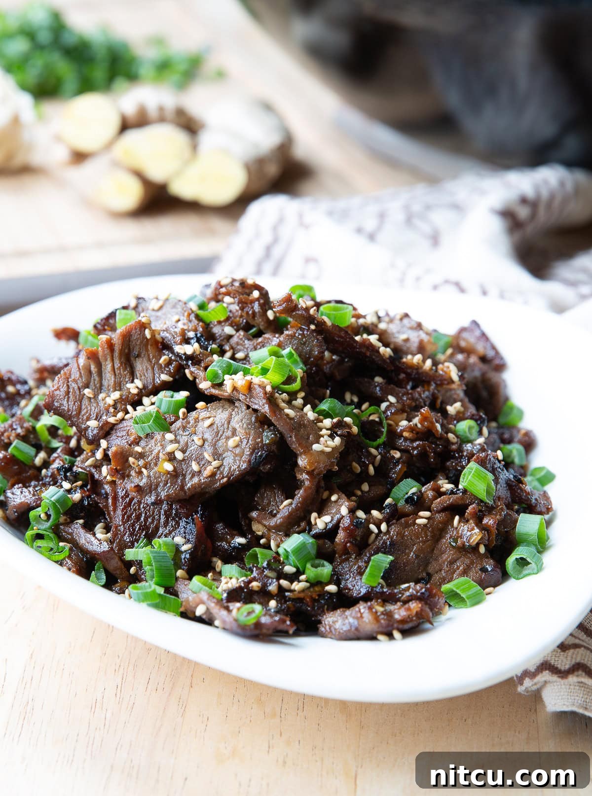 Bulgogi served in a large serving dish topped with sesame seeds and scallions.