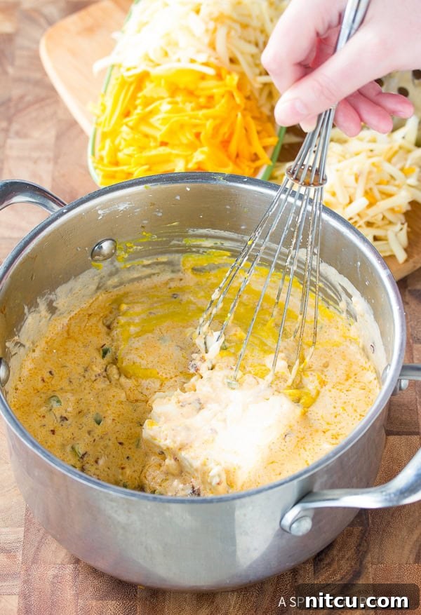 Hand whisking softened cream cheese into the simmering queso dip base, creating a smooth mixture.