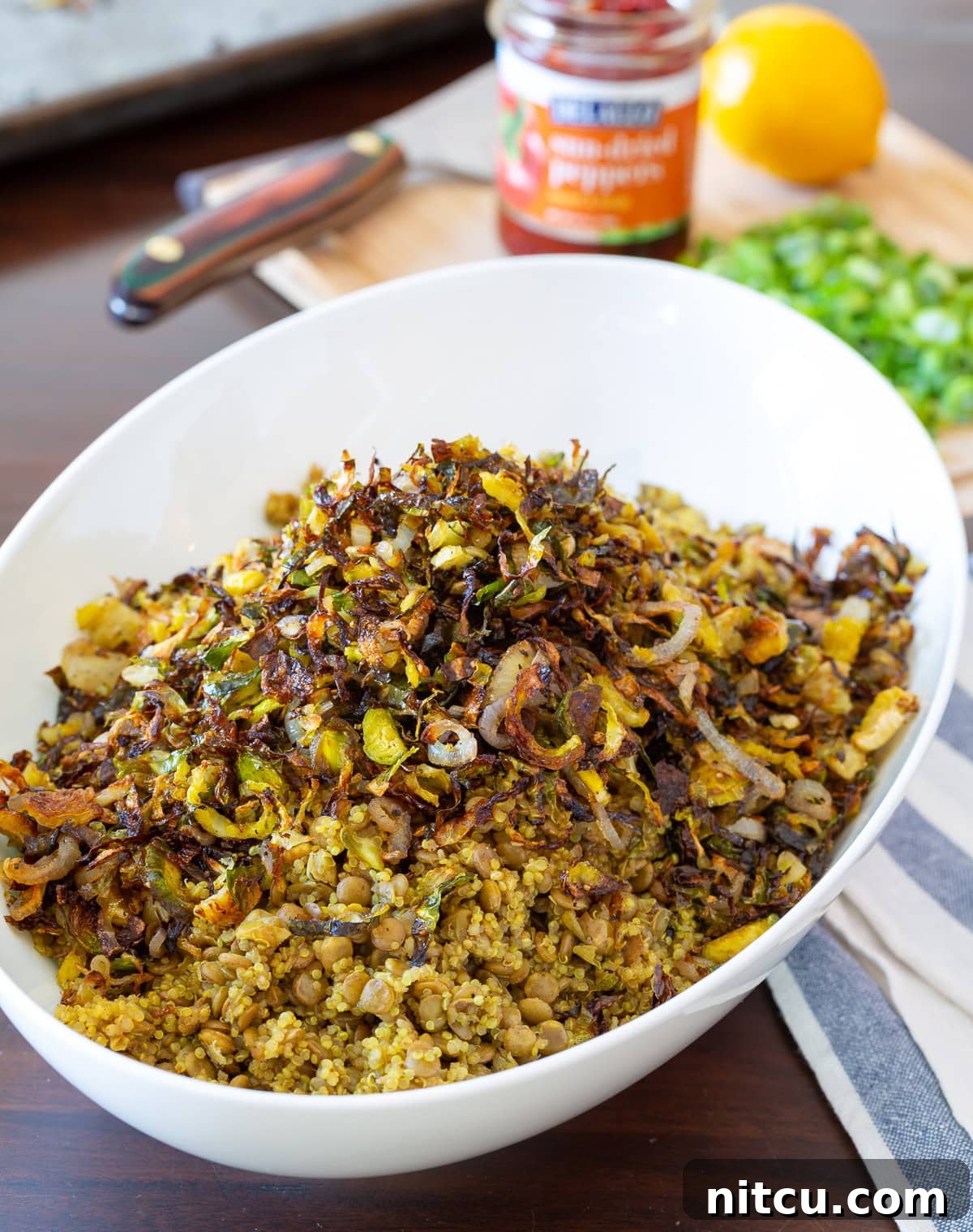 A close-up shot of the finished quinoa lentil salad, showing the perfect blend of fluffy quinoa, firm lentils, and crispy roasted Brussels sprouts in a white bowl.