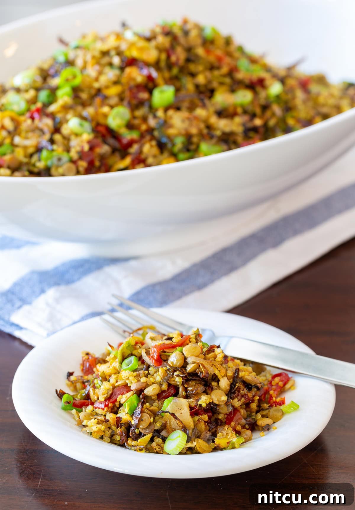 A close-up side view of the quinoa lentil salad, elegantly presented in a white bowl with a fork, emphasizing its satisfying texture and enticing appeal.