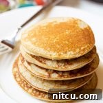 A vibrant close-up of a stack of fluffy paleo pancakes.