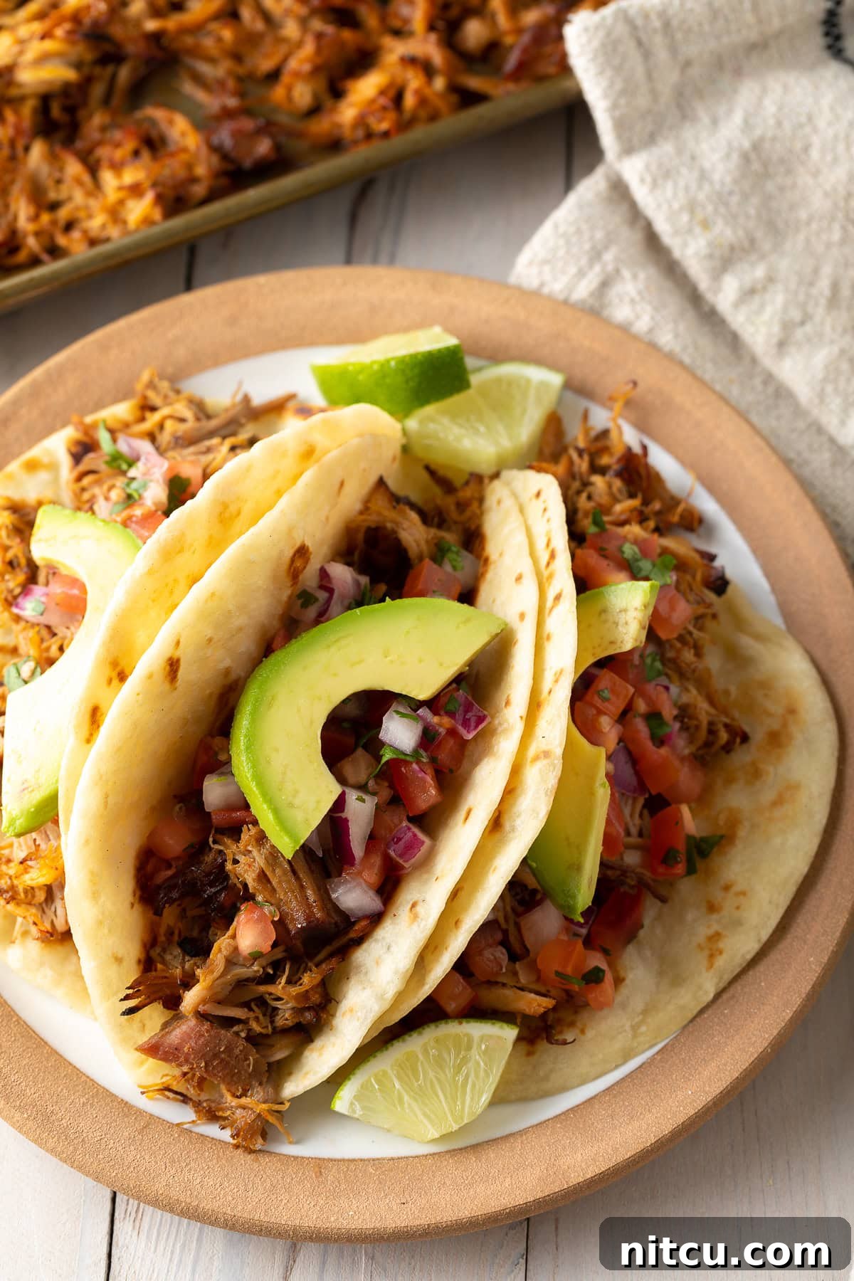 Delicious carnitas tacos loaded with toppings on a plate, showcasing the tender shredded pork.