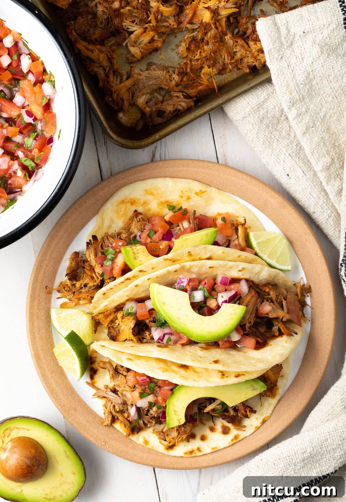 An overhead shot of an easy slow cooker carnitas tacos recipe plated beautifully with fresh toppings.