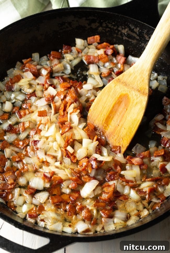 Crispy bacon and sliced onions sautéing in a hot pan, filling the kitchen with an inviting aroma.