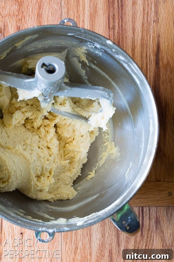 Ingredients for cookie batter being mixed in a stand mixer, showing the process.
