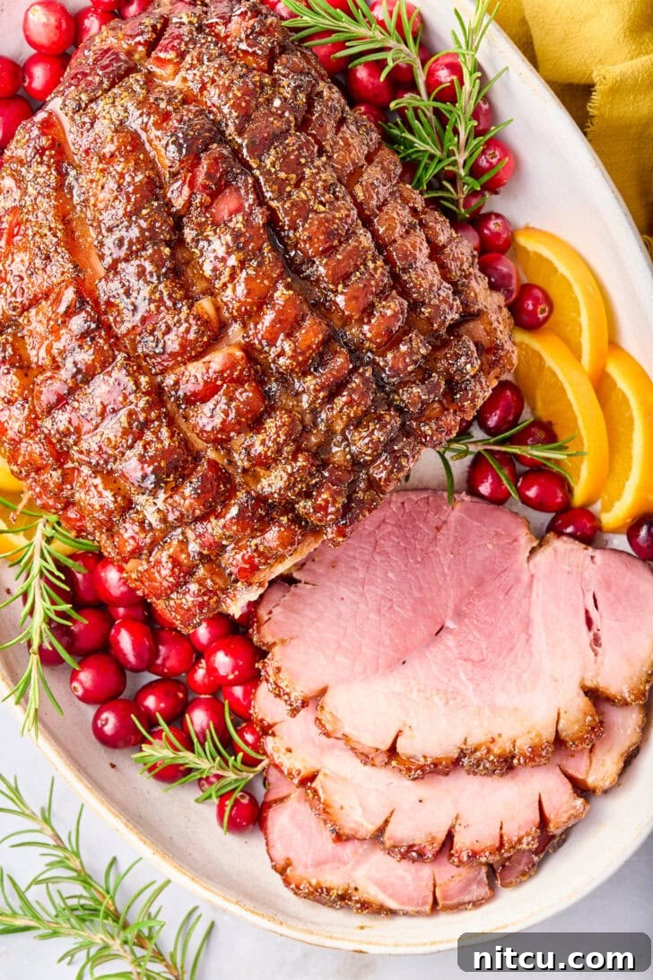 Beautifully sliced Brown Sugar Thanksgiving Ham on a platter, garnished with fresh oranges, cranberries, and rosemary sprigs, ready to be served as a festive centerpiece.