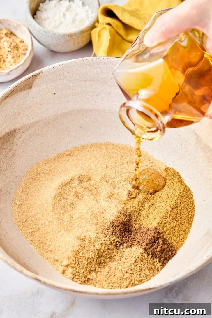 Close-up shot of a chef's hand mixing various ground spices – cumin, coriander, allspice, and cayenne pepper – in a small white bowl, preparing the aromatic blend for the ham glaze.
