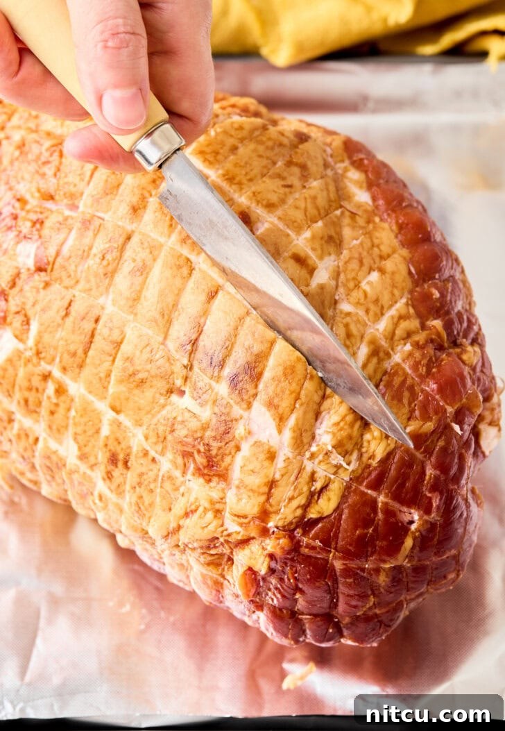 A chef carefully scoring a diamond pattern onto the surface of a raw ham with a sharp knife, a crucial step to allow the glaze to penetrate deeply and create a beautiful presentation.