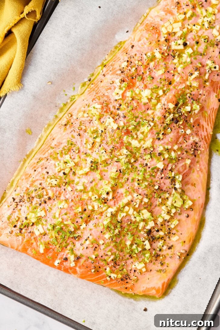 Raw salmon fillet generously coated in the vibrant garlic, lime, and jalapeño marinade, ready for baking.