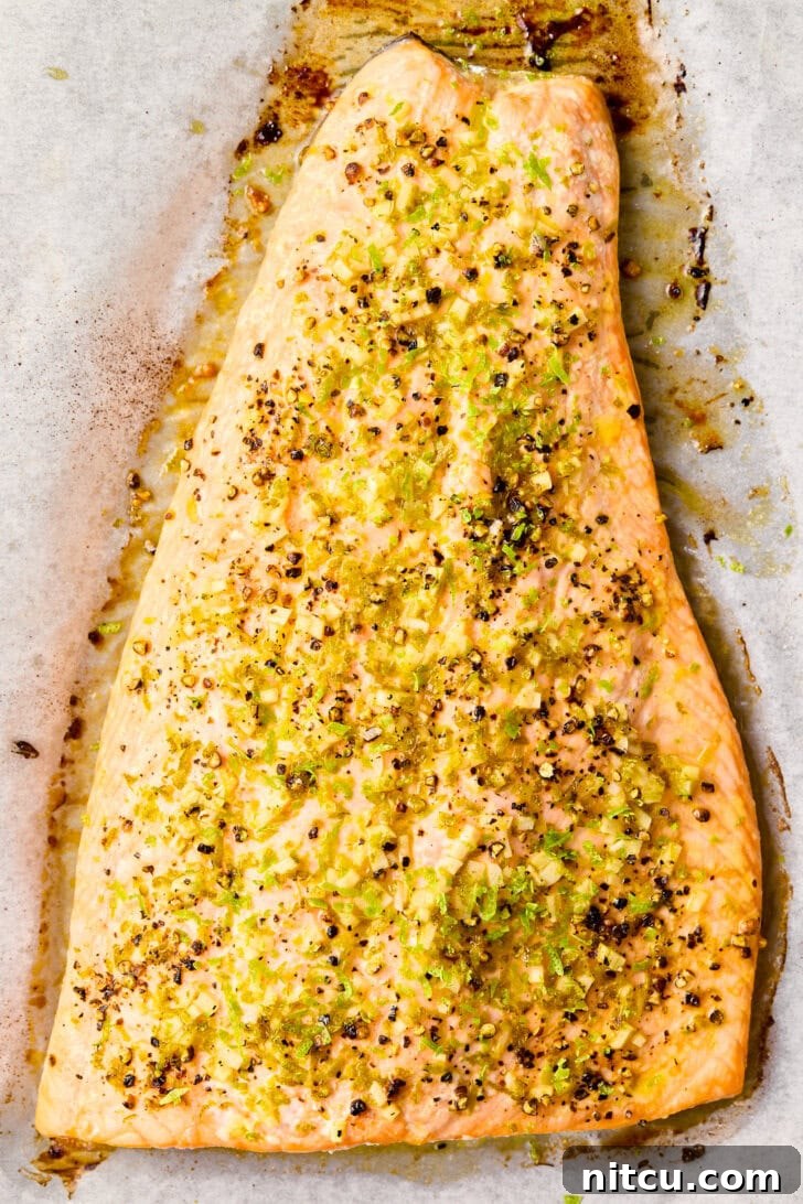 Freshly baked oven salmon with vibrant spices and garnishes, photographed from above on a baking sheet, showcasing its golden-brown crust.